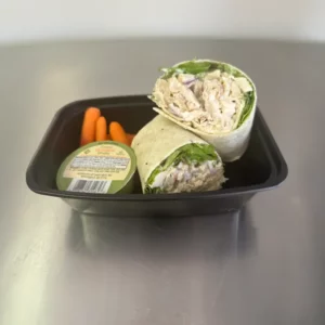 chicken salad wrap in a tray on a table with dressing