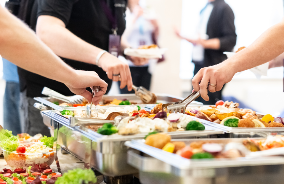 Hands picking up food from buffet catering table at the party.